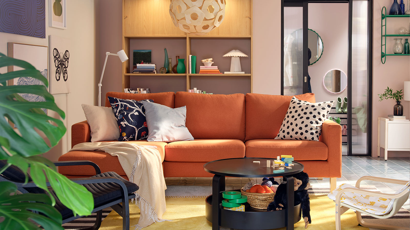 A light living room with a red-brown SALTSJÖBADEN three seat sofa flanked by armchairs, coffee table and toys.