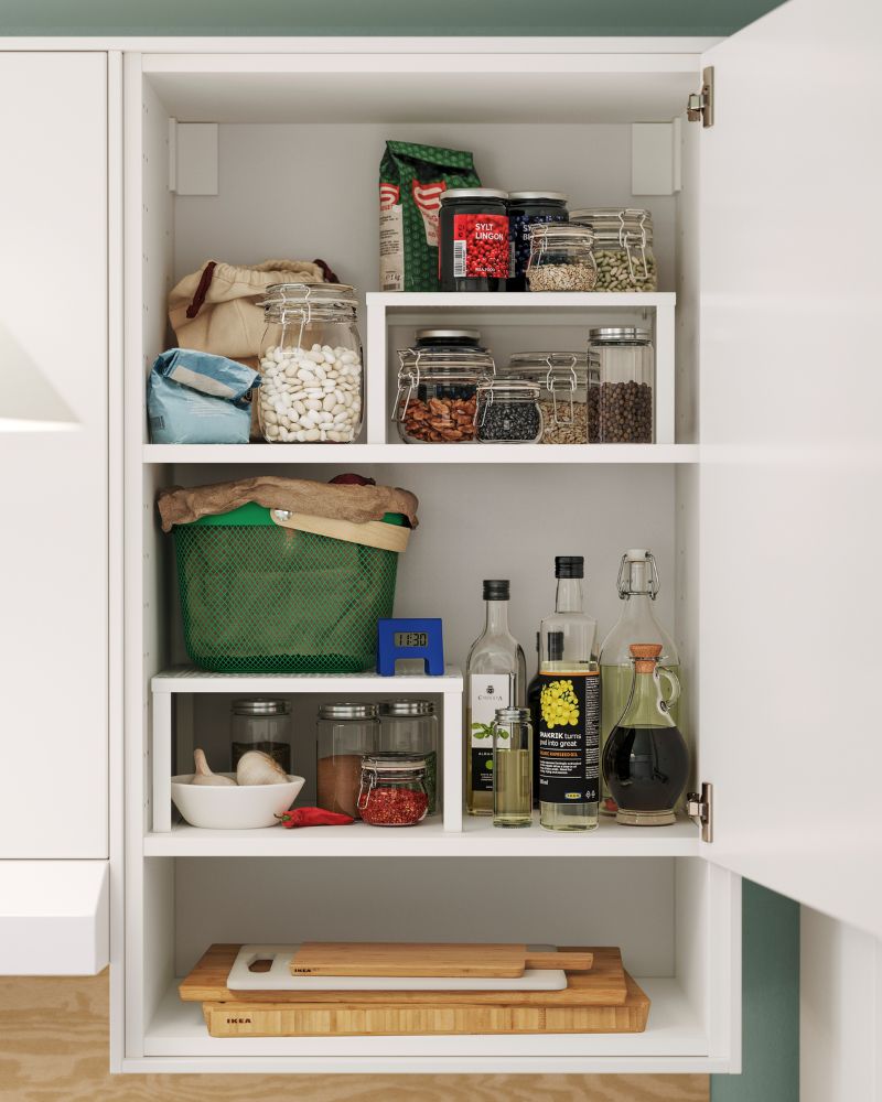 One door of the KNOXHULT tall cabinet is open, revealing containers and food stored on the shelves inside.