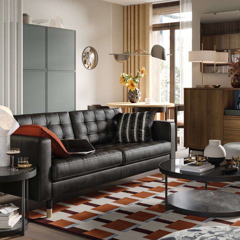 A leather and coated fabric 3-seat sofa stands in a living room near some BESTÅ storage and a RÅDMANSJÖ cabinet.