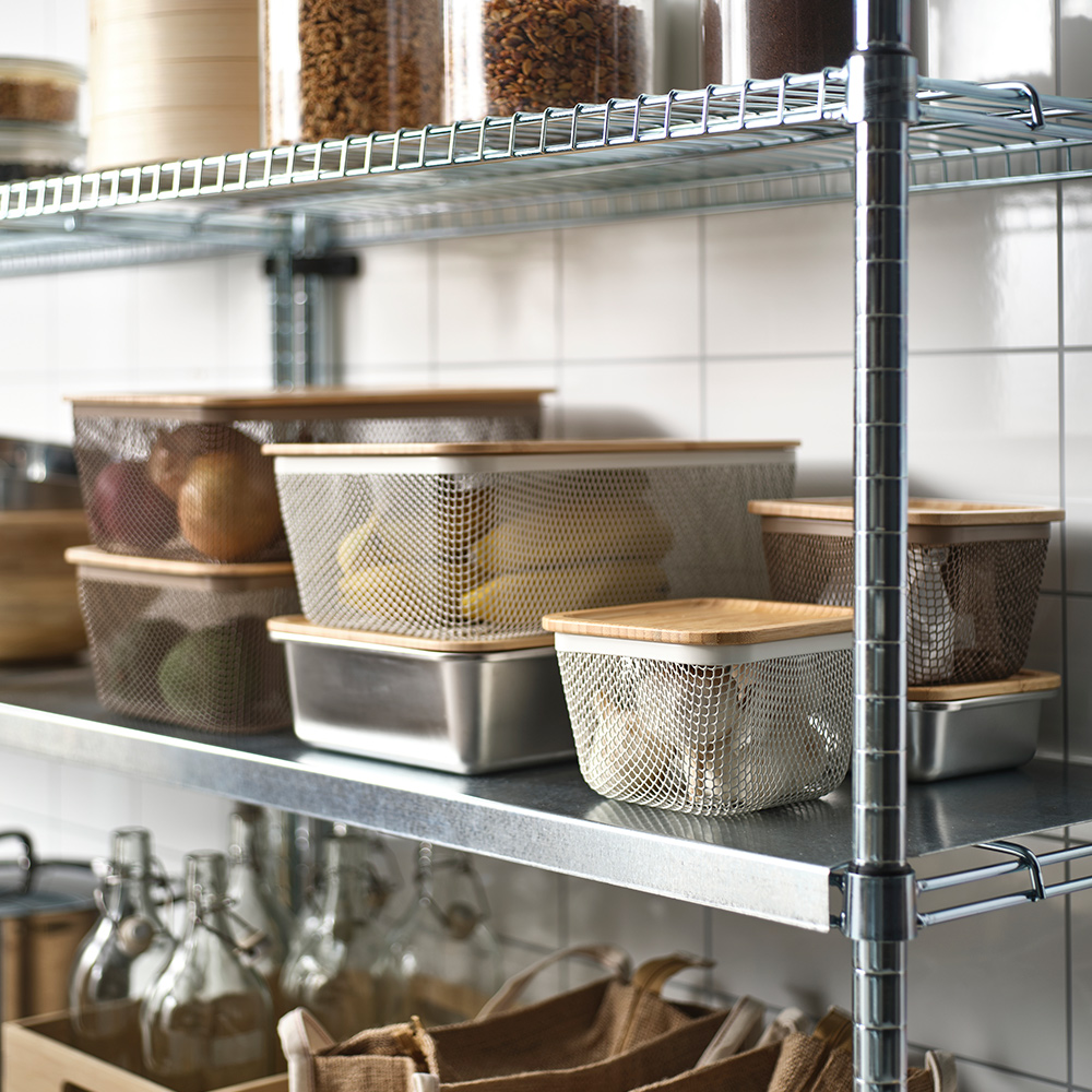 IKEA 365+ food storage baskets with lids filled with garlic, bananas and other food populate an OMAR shelving unit.