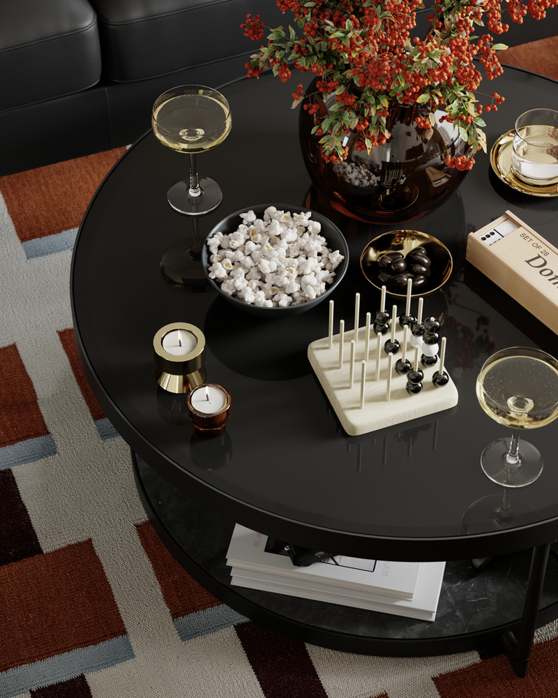 A FRÖTORP coffee table with popcorn, glasses and other things on top of it stands on a STOCKHOLM 2025 rug.