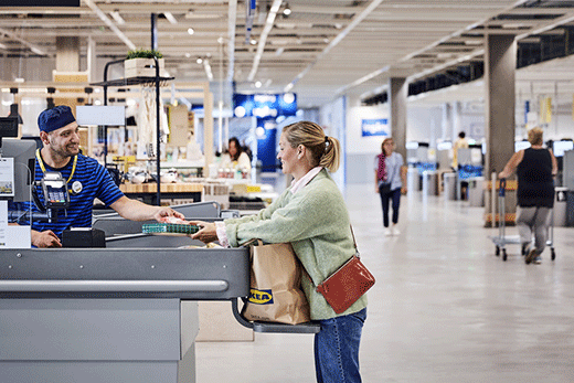 Smiling cashier assisting a customer at the checkout counter of an IKEA store.
