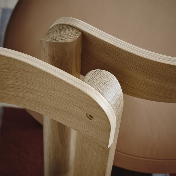 Close-up of the interlocking light oak wood joints and curved backrest of a modern chair.