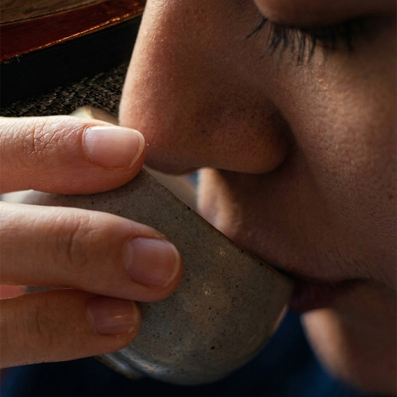 Close-up of hands holding a speckled blue ceramic mug with gentle steam rising from it.